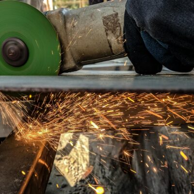 Close-up of a worker using a grinder, creating sparks in a metal workshop environment.